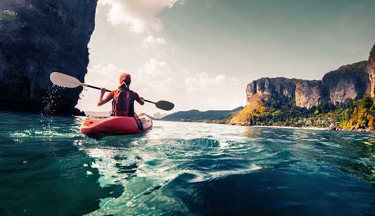 Young adventurous woman kayaking alone